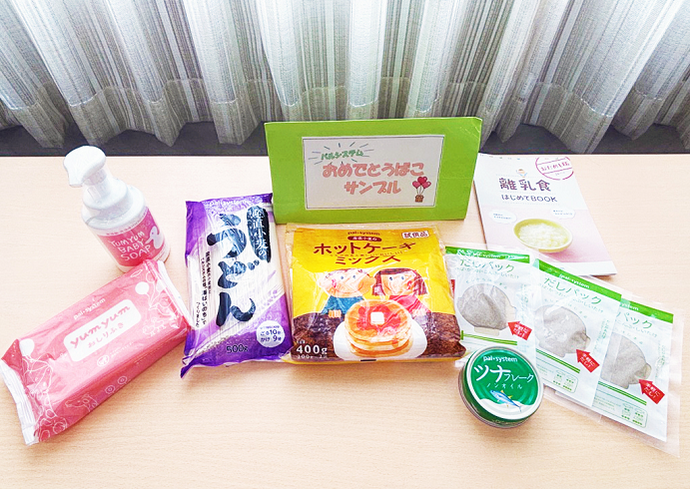 写真:おめでとう箱のサンプル(離乳食の本、おしりふき、赤ちゃん用ソープ、うどん、ホットケーキミックス、だしパック、ツナ缶など)