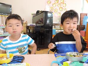 写真：初めてのお弁当を喜んで食べている男の子二人