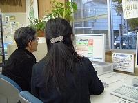 パソコンを見ている2人の背中の写真