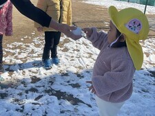 雪玉を触ろうとする0歳児