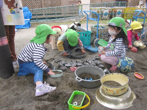 写真：砂場でケーキ屋さんごっこをする子ども