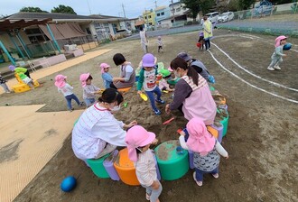 園庭に新しくできた砂場に子ども達が集まって、砂遊びをしている写真