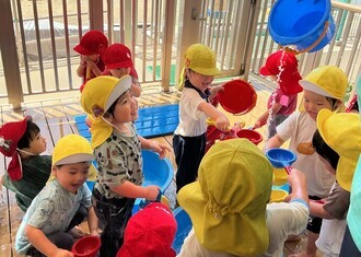 テラスで水遊びを楽しむ子ども達の写真