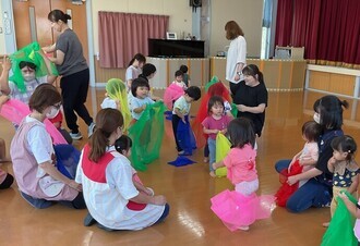 ムーブメント遊具の色とりどりのスカーフで自由に遊ぶ子ども達の写真