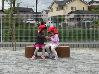 ベンチに座ってキラキラした石を見せ合う女の子2人の写真