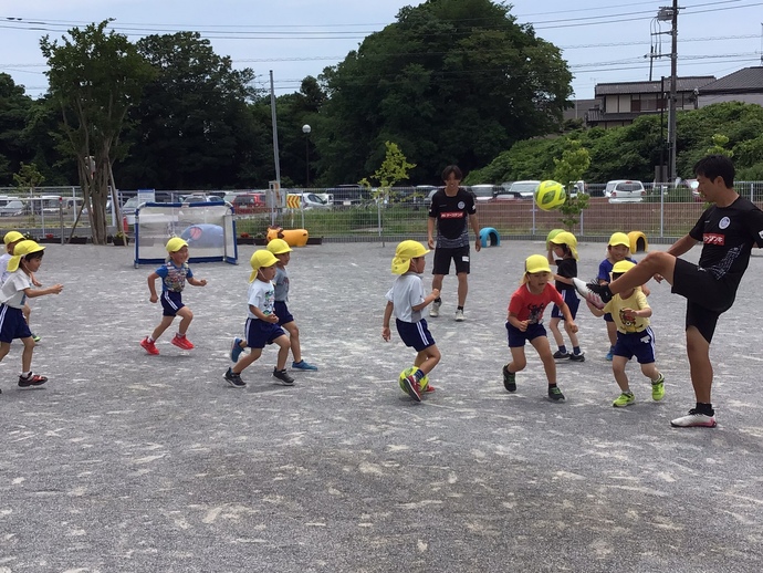 コーチとサッカーをする子どもの写真