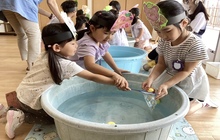 水に浮かぶおもちゃすくいをする子ども達の写真。