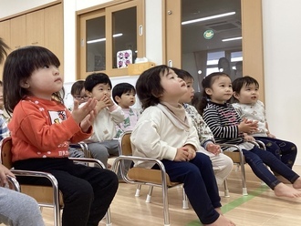 保育士の話に一生懸命、耳を傾ける1歳児クラスの子ども達の写真。