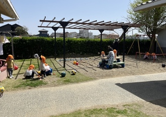 2歳児らっこ組の子ども達が中庭で遊んでいる写真
