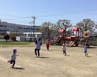 保育所の園庭で鬼ごっこをする子ども達の写真