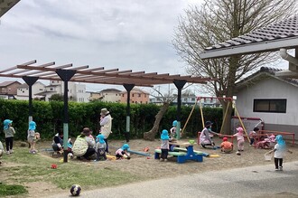 1、2歳児の子ども達が保育所の中庭で砂遊びをしている写真