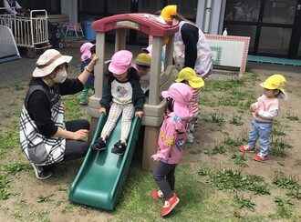中庭で遊ぶ1、2歳児の写真