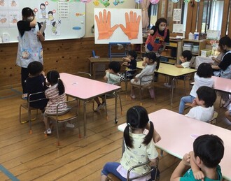 看護師から手洗い指導の話を聞いている3歳児の写真