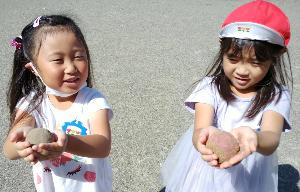 写真：作成中のどろだんごを嬉しそうに見せてくれる女の子二人