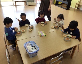 テーブルに座って給食を食べる子ども