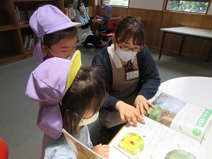 写真：地域の図書館で調べることを手伝ってもらう幼稚園生