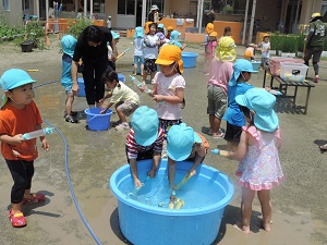 写真：幼稚園の庭で水遊びを楽しむ園児