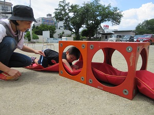 写真：園庭にできた小さなトンネルくぐりに挑戦する年少児