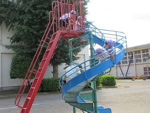 写真：学校の滑り台を滑り降り楽しむ年長児
