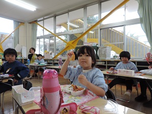 写真：誕生会でお楽しみ弁当を喜んで食べている年中組女児