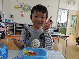 写真：ニコニコ笑顔でお弁当を食べている年長男児