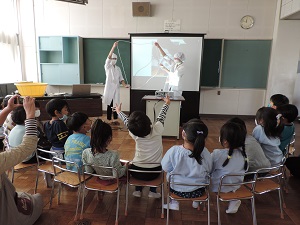 写真：年長児が体験給食で栄養士さんから鍋の大きさを教えてもらっているところ