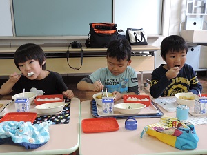 写真：大きな口でカレーを味わう年長男児3人組