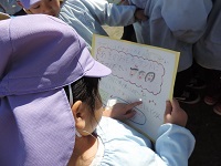 写真:小学生が持ってきてくれた招待状に関心を示し読んでいる幼稚園児の姿