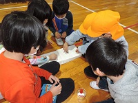 写真:手作りおもちゃの遊び方を幼稚園生に丁寧に教えてくれている1年生