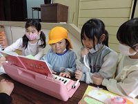 写真:鍵盤ハーモニカの音が出るように1年生が息を吹き込み,幼稚園生が鍵盤を弾いている