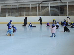 写真:氷上でスケート靴を履いたまま立ち上がる練習をしている