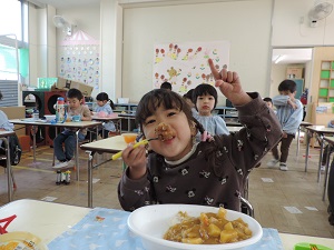 写真：カレーのお弁当をおいしく食べる年少女児