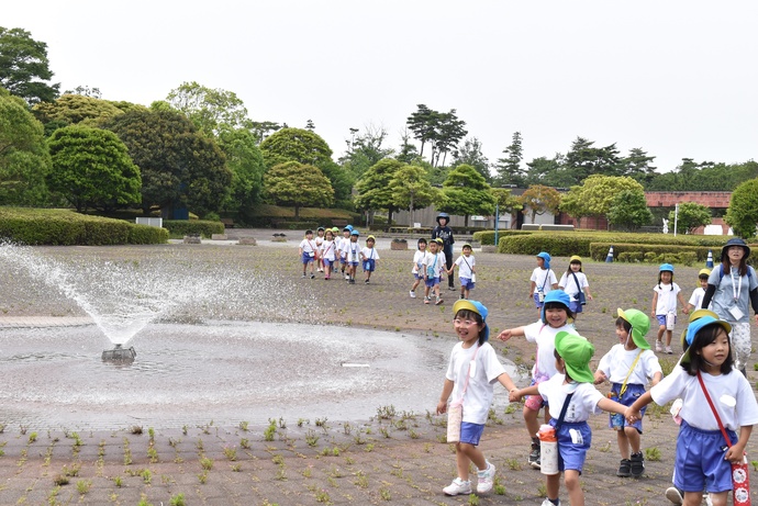 噴水のそばを歩く園児