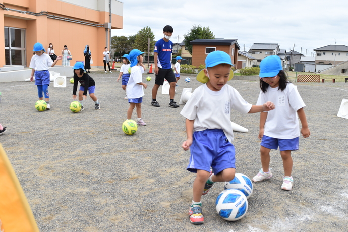 ボールを蹴って追いかける男の子と女の子