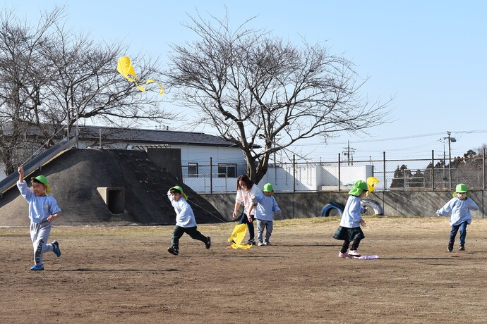 校庭で凧揚げをする幼児