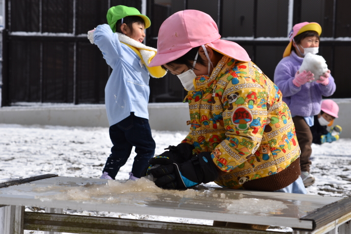 座って雪を固める園児