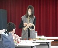 写真：講師がしめ縄を使ったドア飾りの作り方を説明している様子