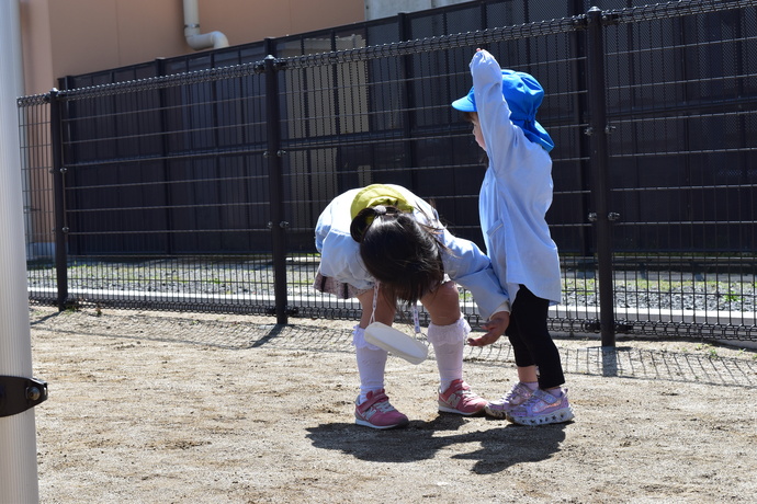 小さいお友達の膝の汚れを払ってあげる園児