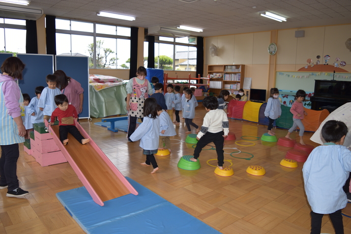 遊戯室で滑り台やピョンピョン岩で遊ぶ幼児