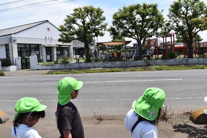 道路の向かい側から手を振る園児