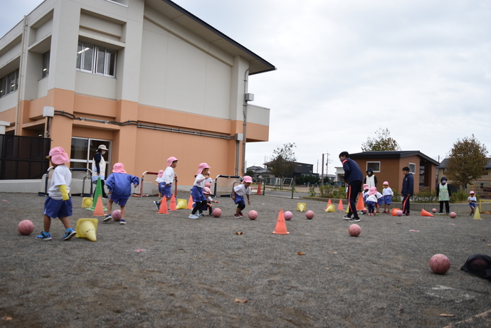 三角コーンをボールで倒すゲームをする園児