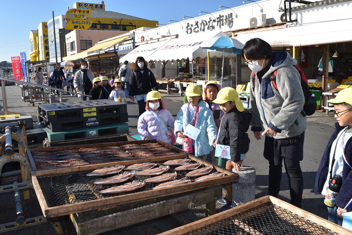 すだれに干された干物を見る園児たち