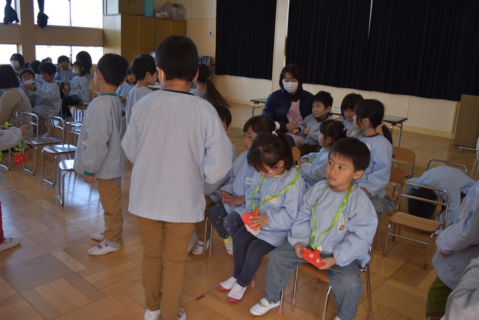 プレゼントのペンダントを首にかける園児