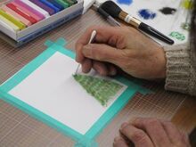 写真:綿棒を使ってクリスマスツリーを描いている様子