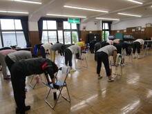 写真：椅子の座面を持って背中を伸ばしている様子