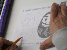 写真：利き手と反対の手でお題「だるま」を描いている様子