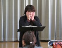 写真:下顎を両手で軽く押さえて発声練習している様子