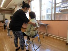 写真:骨盤と背骨の連動を意識した姿勢を講師が指導している様子